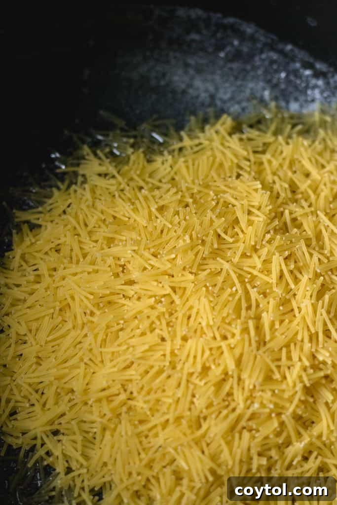 Vermicelli noodles being toasted to a golden brown in butter within a pot, ready for the rice to be added.