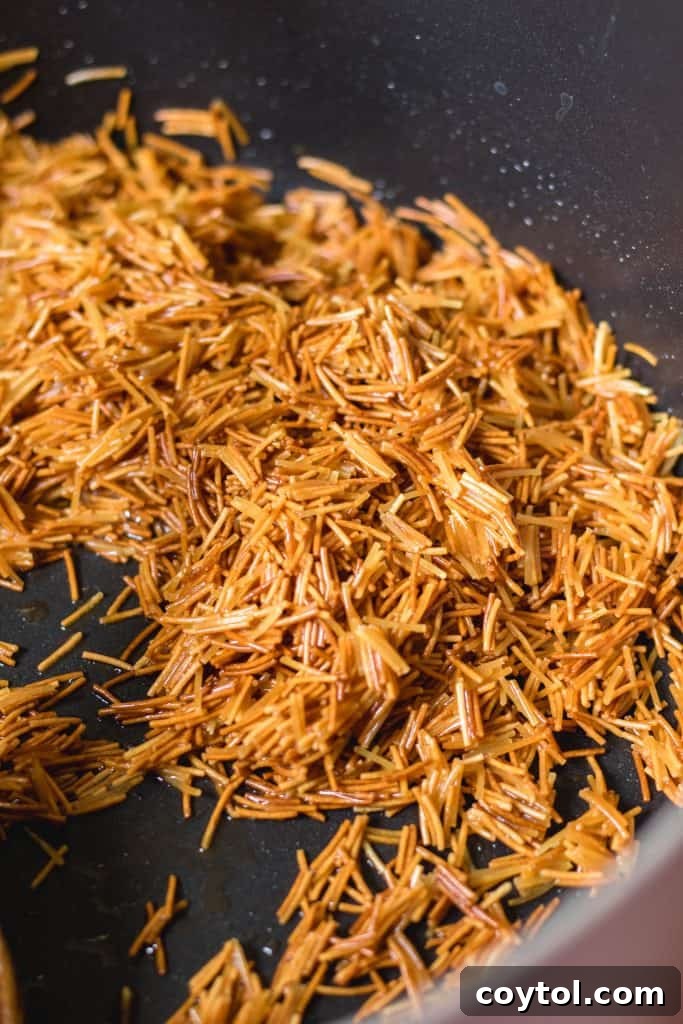 Close-up of perfectly toasted golden vermicelli noodles in a pot, ready for the next step of making Lebanese rice.