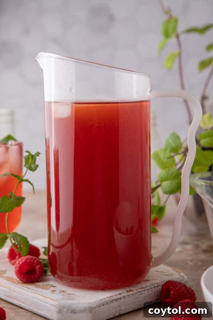 Pitcher of homemade Raspberry Iced Tea with fresh raspberries and ice
