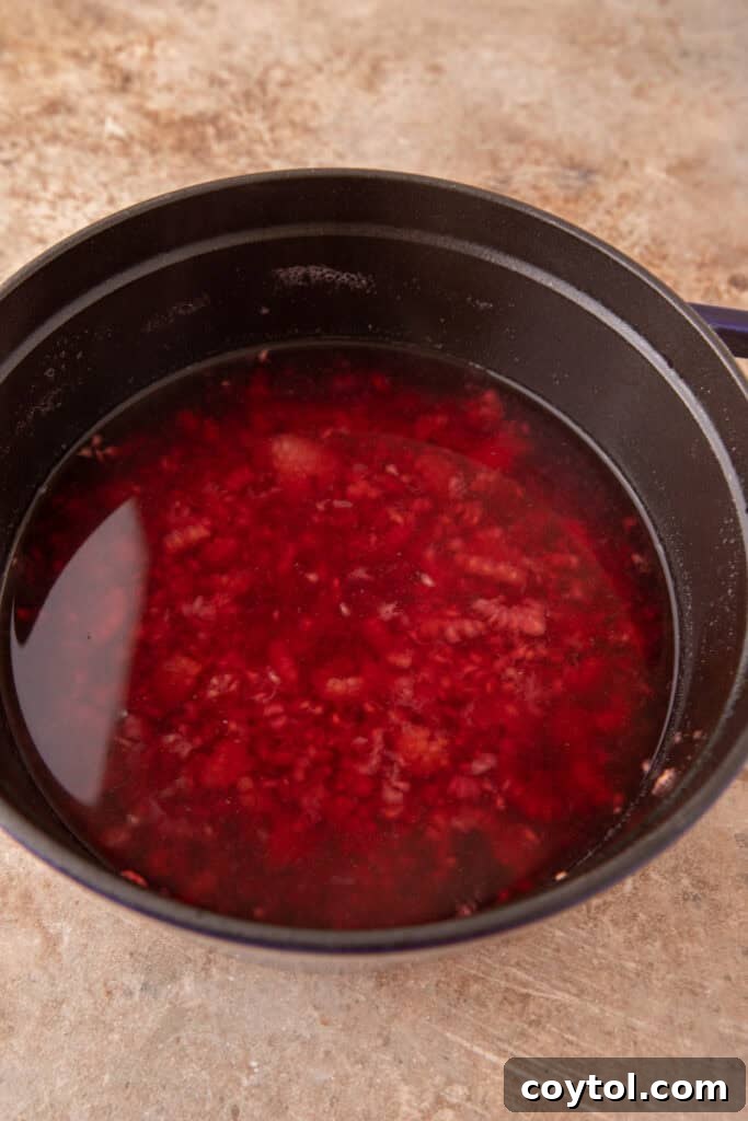 Raspberries simmering in a pot with water and sugar for syrup