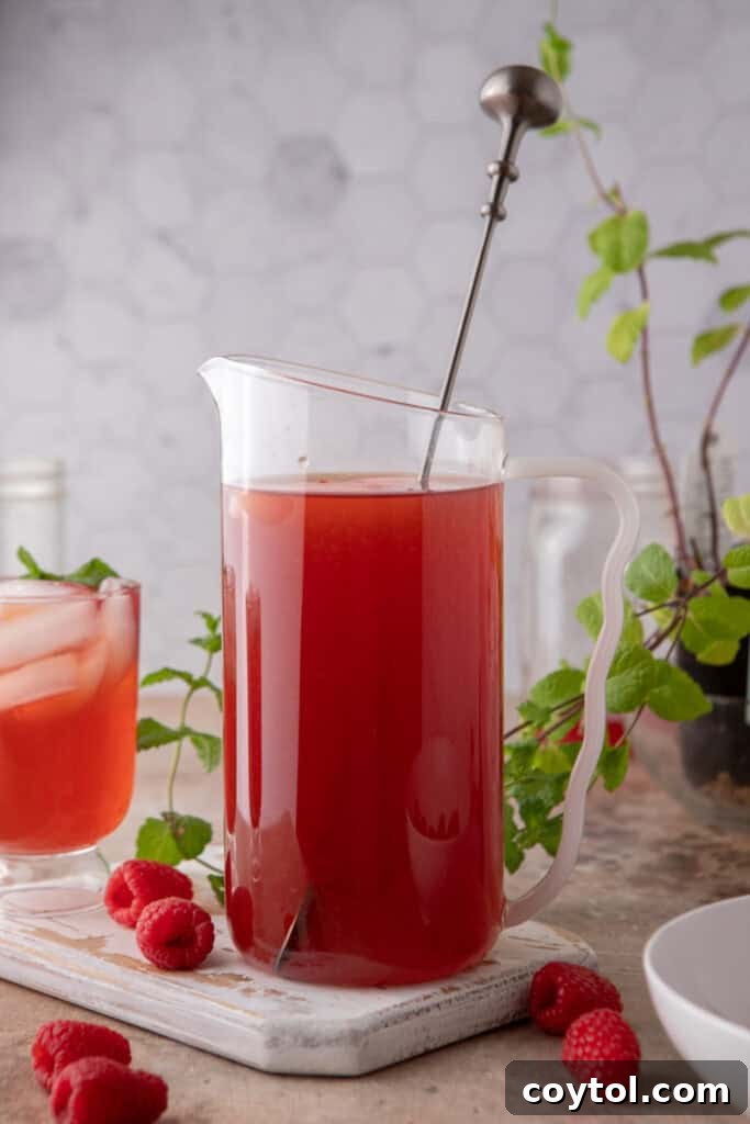 Side shot of the raspberry iced tea recipe in a pitcher on a table
