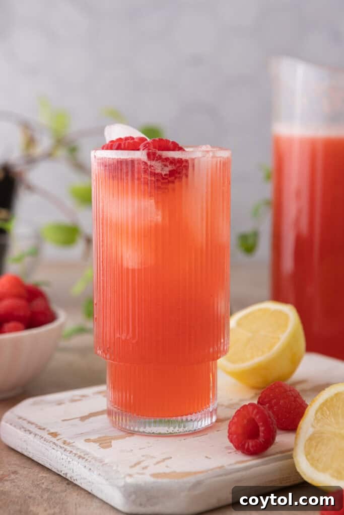 A glass of homemade raspberry lemonade with ice and fresh raspberries