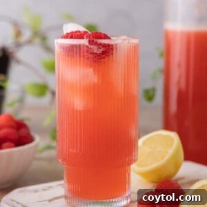 A glass of homemade raspberry lemonade with ice and fresh raspberries