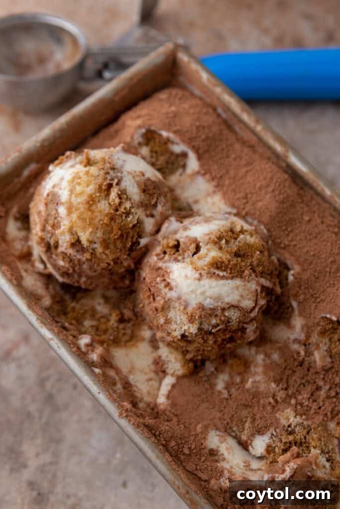A loaf pan filled with the first layer of no-churn tiramisu ice cream, showcasing the creamy base and a hint of espresso-soaked ladyfingers.