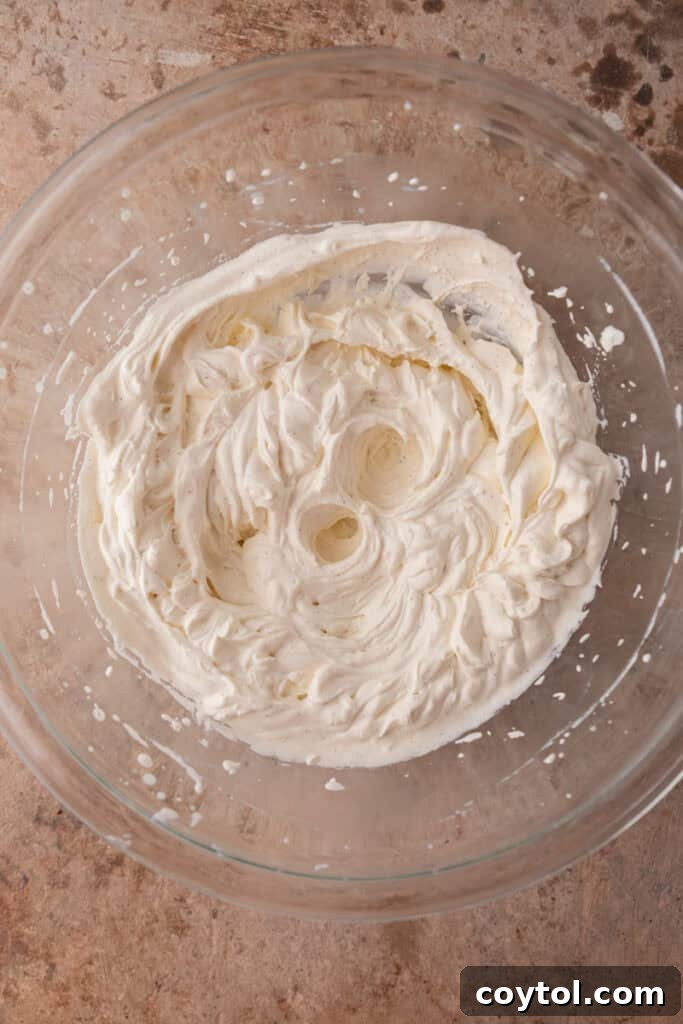 Whipped heavy cream forming stiff peaks in a mixing bowl.