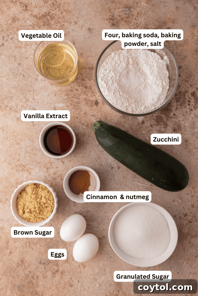 A flat lay photograph of fresh zucchini and other key ingredients for making zucchini bread laid out on a kitchen counter.
