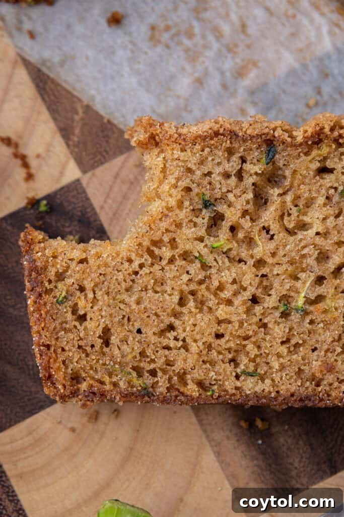 Close-up overhead view of a slice of zucchini bread with a bite taken out, showing its moist interior and spiced flavor.