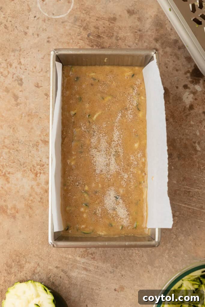 Raw zucchini bread batter poured into a loaf pan, ready for baking.