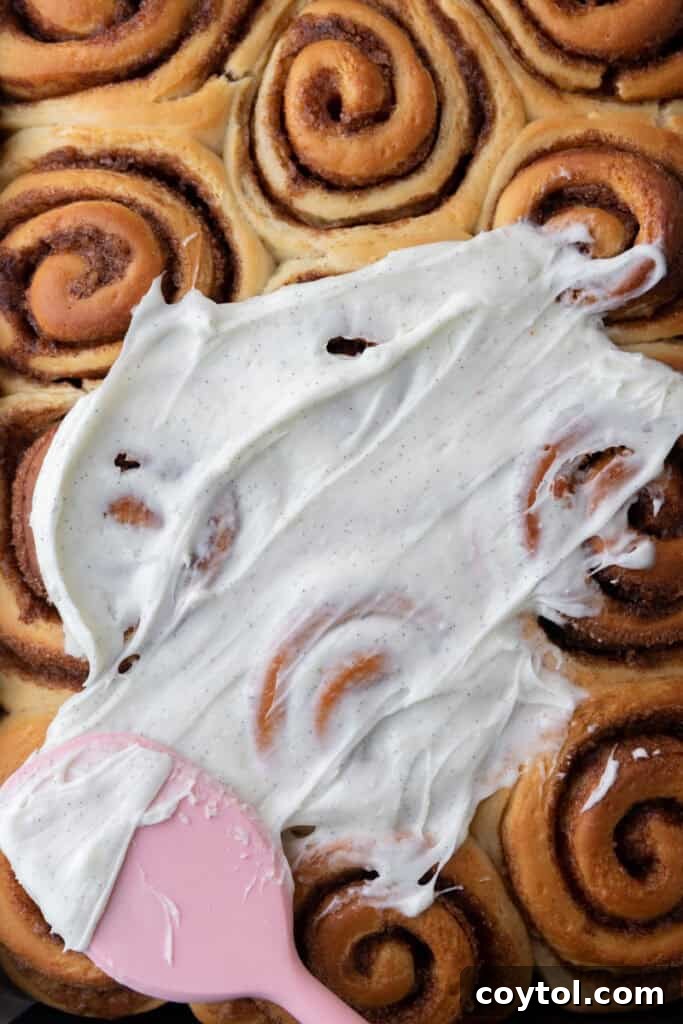 Generous amount of cream cheese frosting beautifully spread over the warm, baked cinnamon rolls.