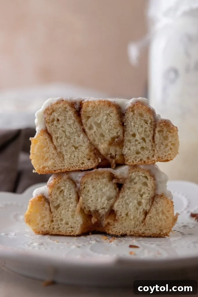 A Sourdough Discard Cinnamon Roll neatly split in half, showcasing its tender, layered interior and the rich, gooey cinnamon filling.