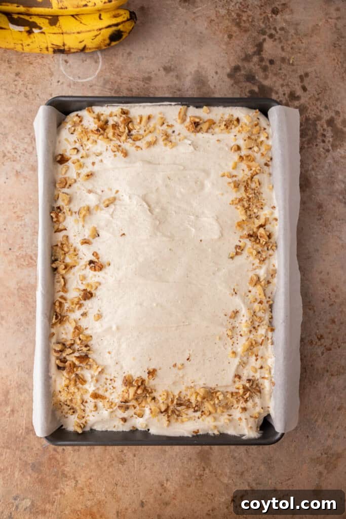 An overhead shot of the fully frosted banana cake in the pan, covered in smooth cream cheese frosting.
