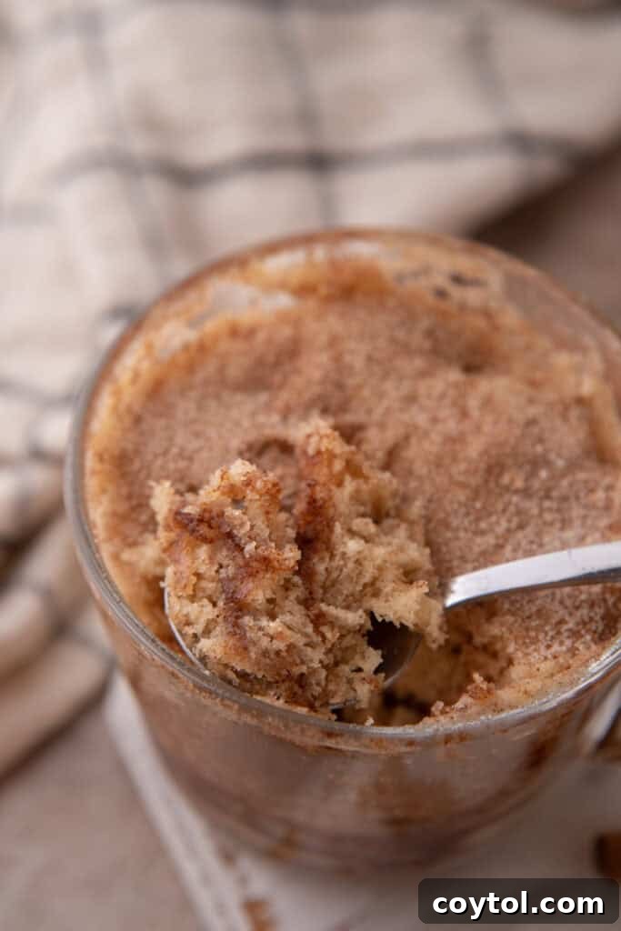 snickerdoodle mug cake recipe in a cup getting scooped