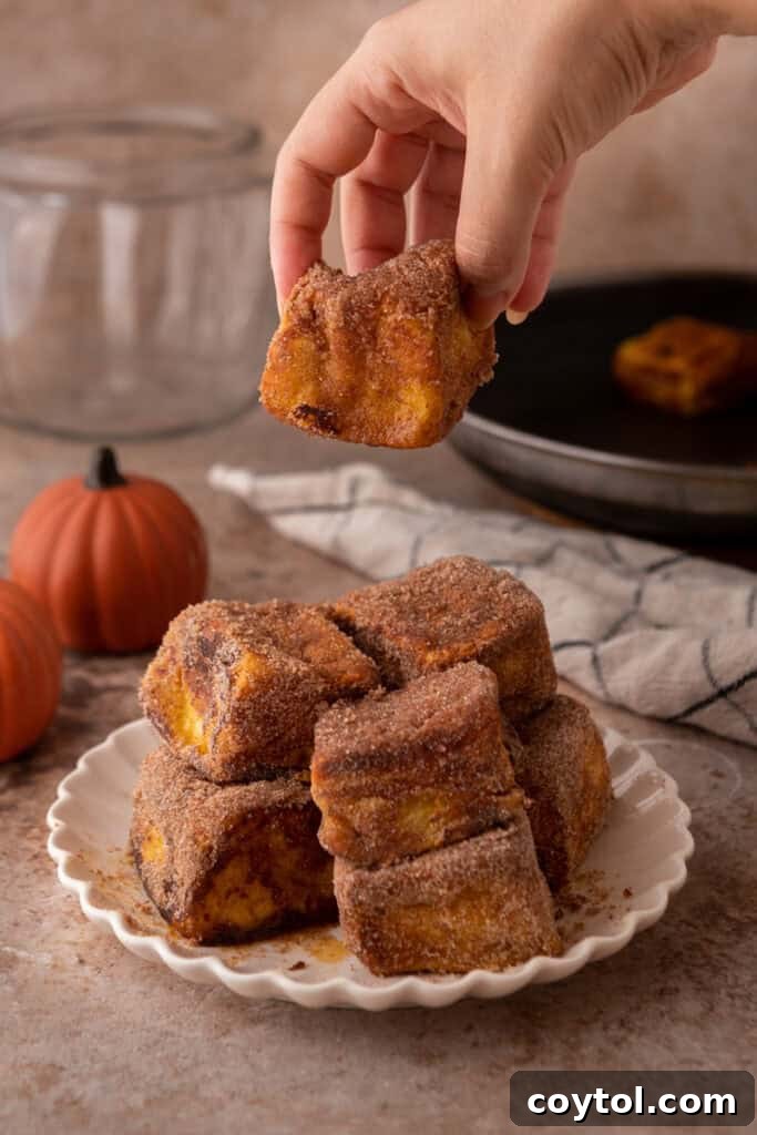 a hand putting a Hawaiian Roll Pumpkin French Toast on a plate