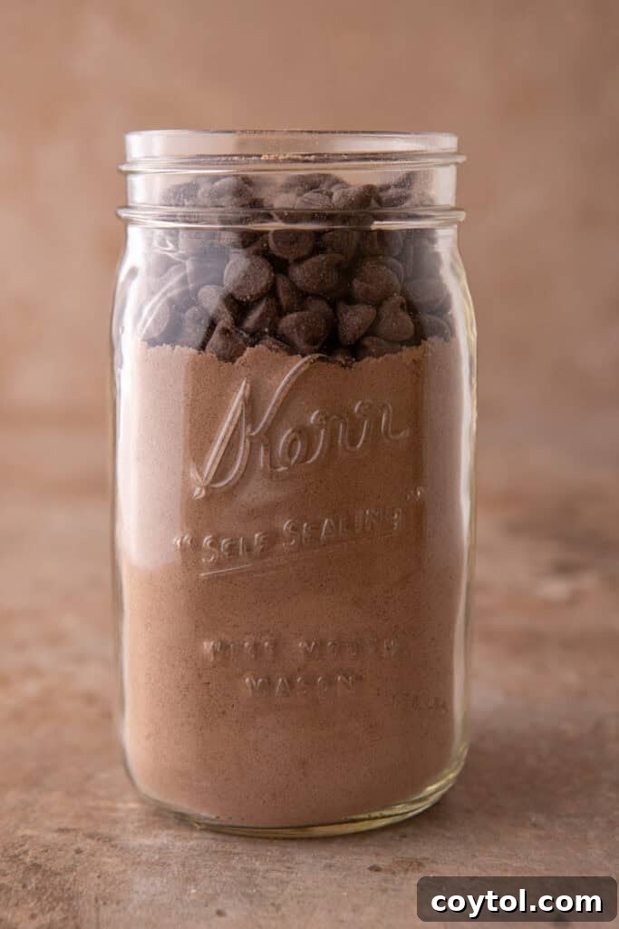 Mixed dry ingredients being transferred into a mason jar for brownie mix