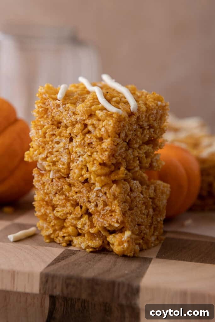 Autumn Pumpkin Rice Krispie Perfection 2 Close-up of freshly made pumpkin rice krispie treats, drizzled with white chocolate, in an autumnal setting.
