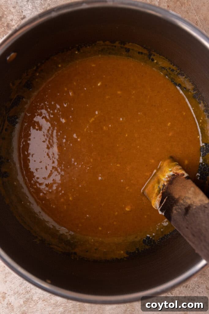 Autumn Pumpkin Rice Krispie Perfection 7 Pumpkin puree, spices, and vanilla extract being stirred into melted marshmallows and butter.