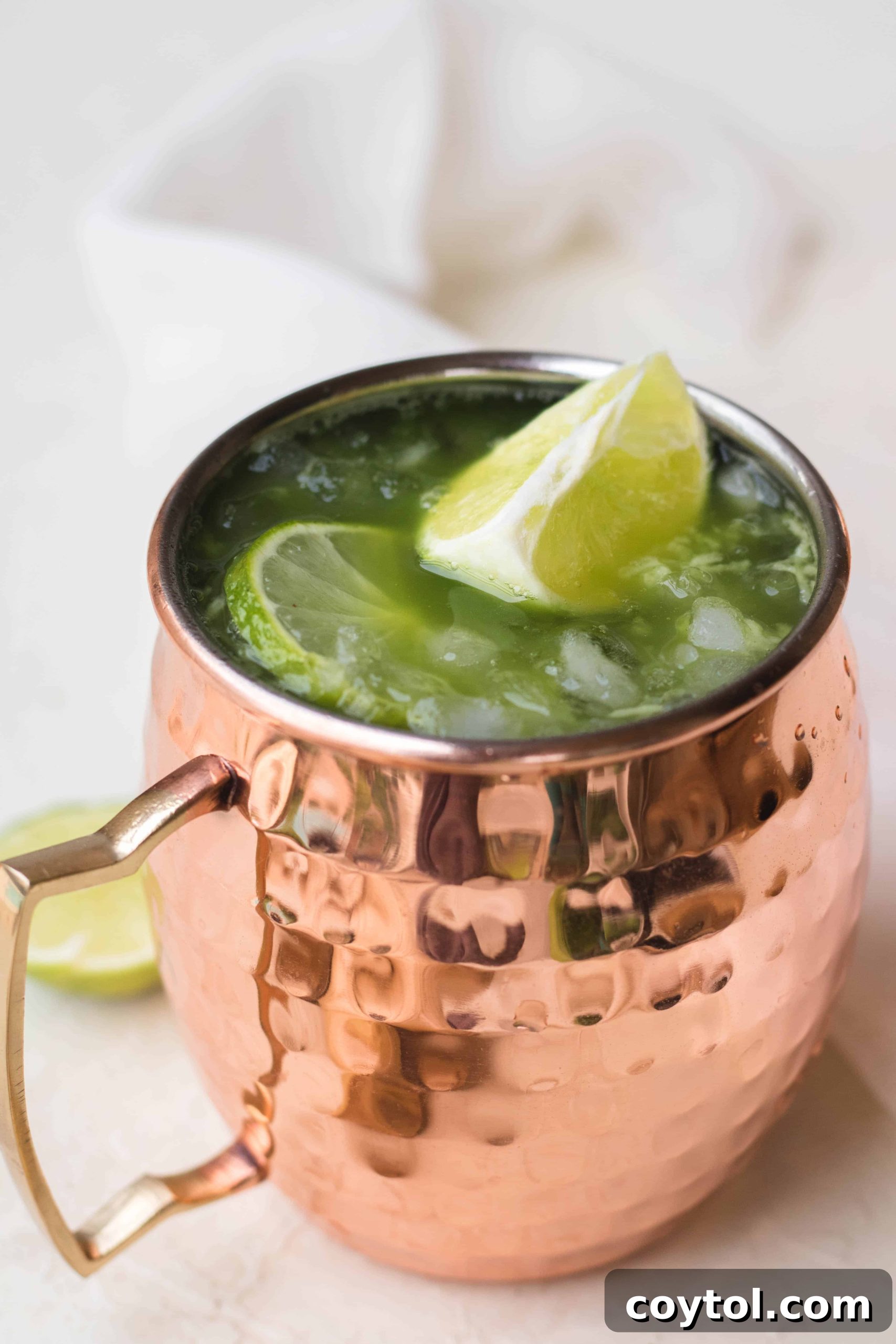 Two Virgin Matcha Moscow Mules with crushed ice and lime wedges, showcasing their vibrant green color