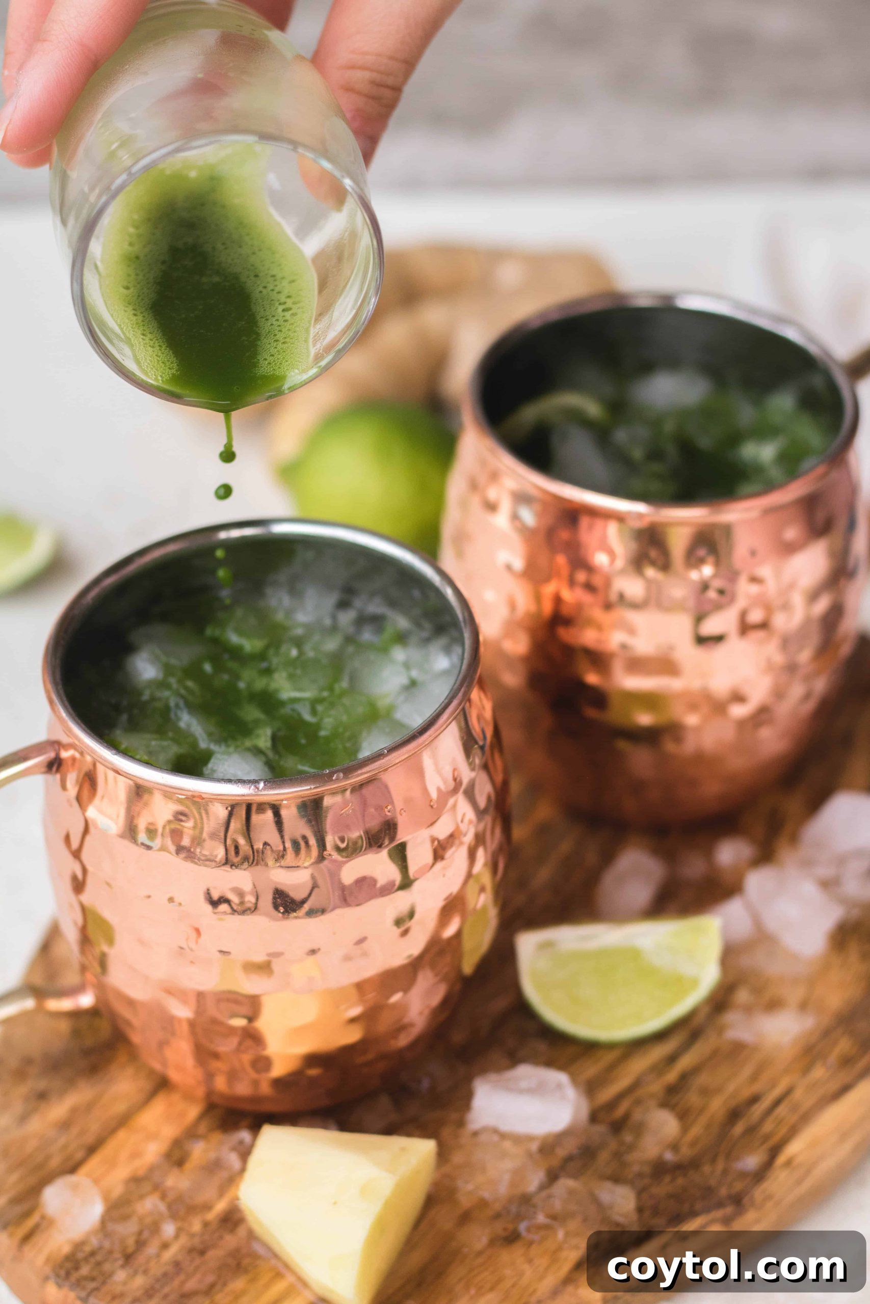 Garnishing a Virgin Matcha Moscow Mule with a lime slice and fresh ginger