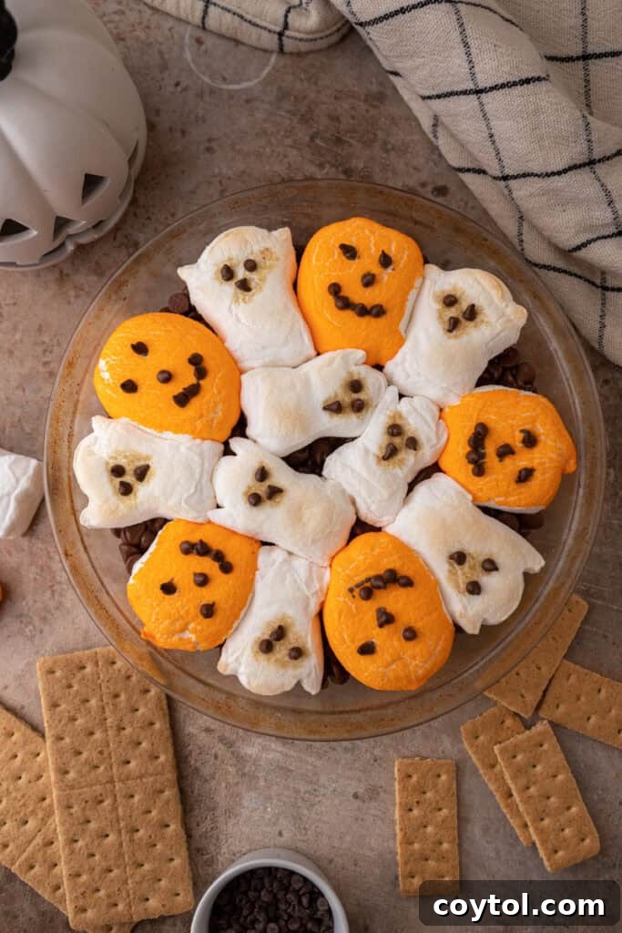 Wicked Good Halloween Smores Dip 7 chocolate chips in a baking dish with marshmallows on top fully baked and golden