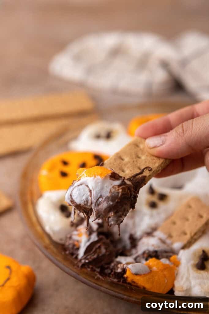 Wicked Good Halloween Smores Dip 10 Halloween S'mores Dip Recipe getting scooped up again, showing gooey texture