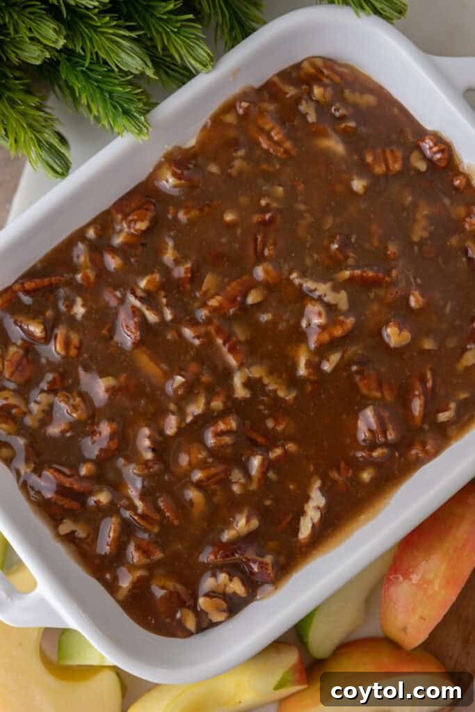The pecan topping carefully spread over the cream cheese layer in the dish.