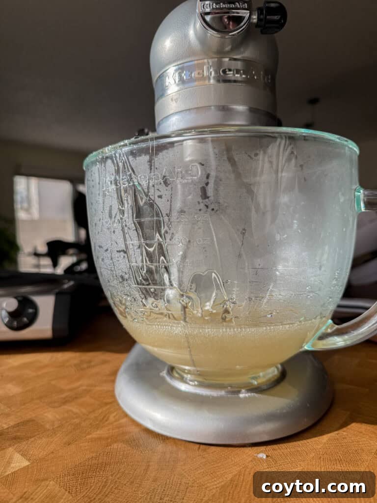 hot sugar syrup being poured into bloomed gelatin in a stand mixer