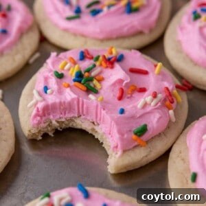 Pillowy Old-Fashioned Sour Cream Sugar Cookies 15 Soft sour cream sugar cookie with pink frosting and rainbow sprinkles, with a bite taken out to show the tender interior.