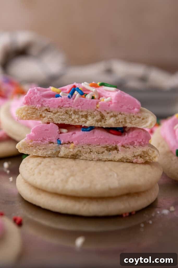 Pillowy Old-Fashioned Sour Cream Sugar Cookies 4 Soft sour cream sugar cookies stacked with a frosted cookie cut open to show the fluffy interior.
