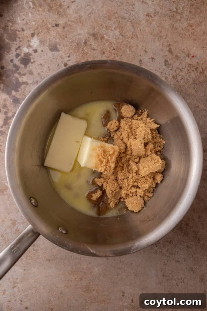 Unsalted butter and brown sugar melting together in a saucepan over medium heat, beginning the toffee creation process.