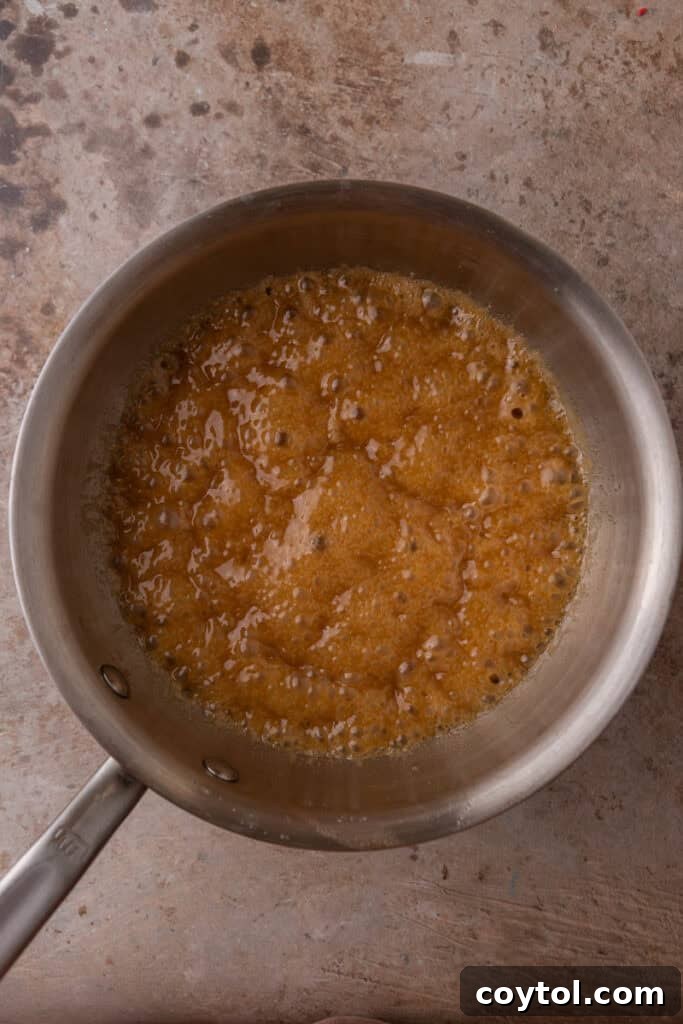 Bubbling brown sugar and butter mixture cooking in a pan, indicative of the rolling boil required for perfect toffee consistency.