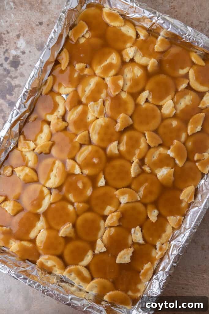 Warm, golden toffee carefully poured and spread evenly over the layer of Ritz crackers on a sheet pan.