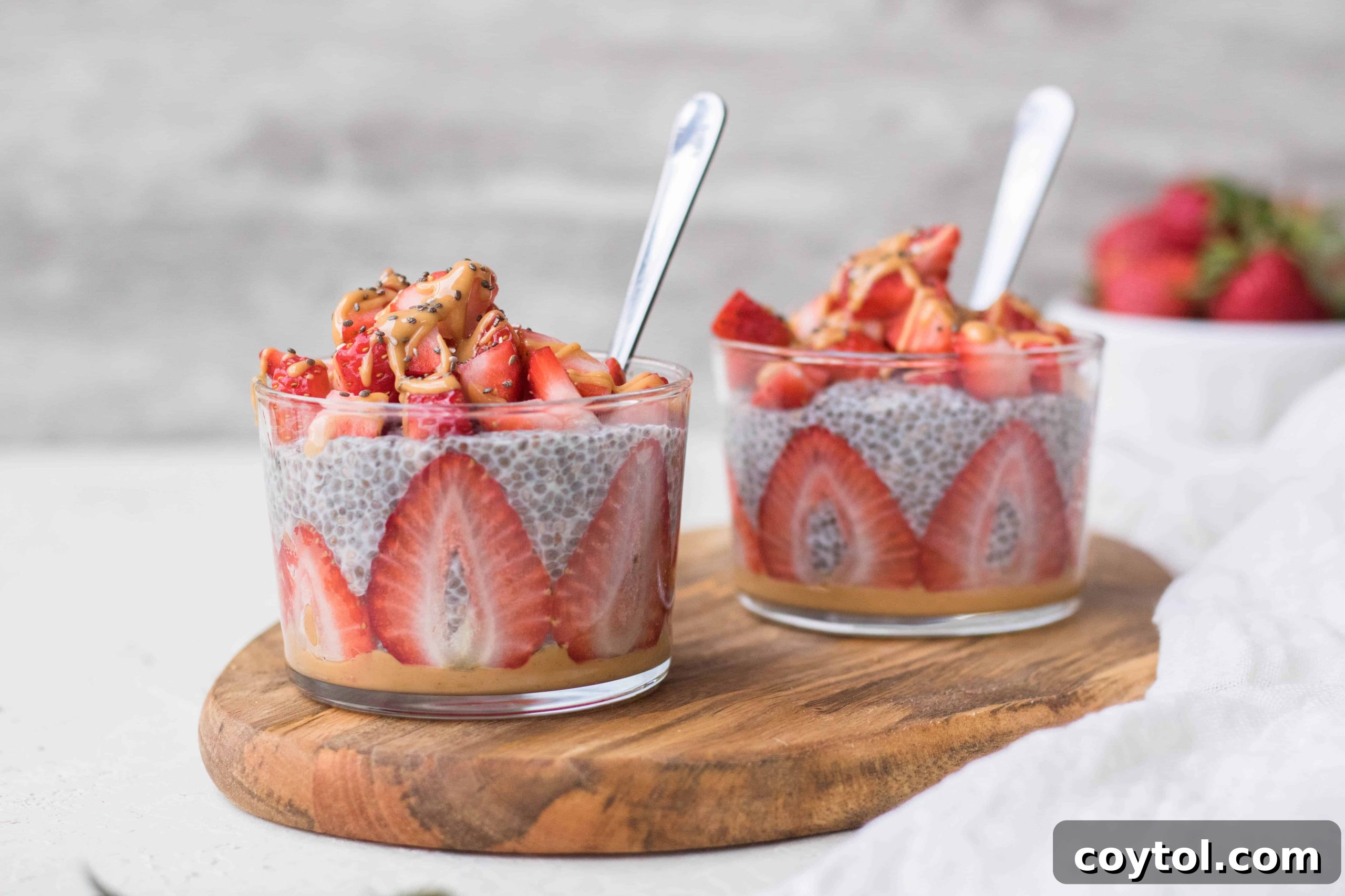 Strawberry Peanut Butter Chia Dream 2 Vibrant strawberry peanut butter chia seed pudding in a glass cup, garnished with fresh strawberries and a drizzle of peanut butter.