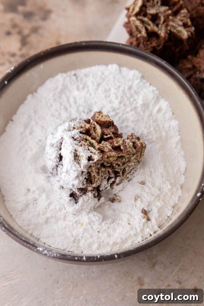 Chocolate cereal squares being tossed in powdered sugar for the classic Muddy Buddy coating.