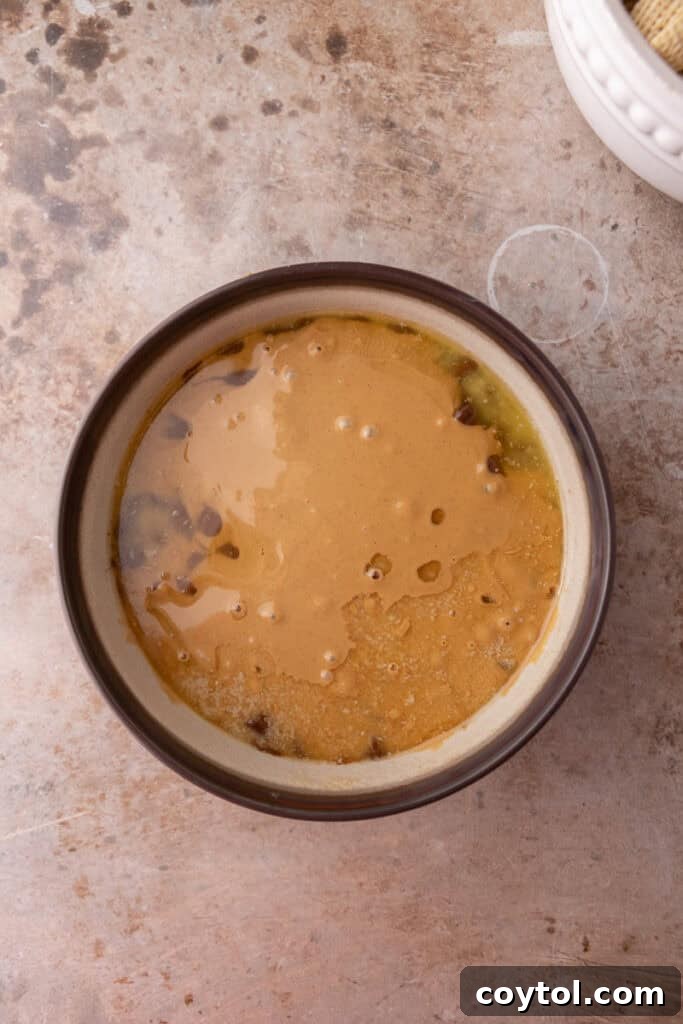 Melted chocolate, peanut butter, and butter mixture in a bowl, smooth and ready to coat cereal.