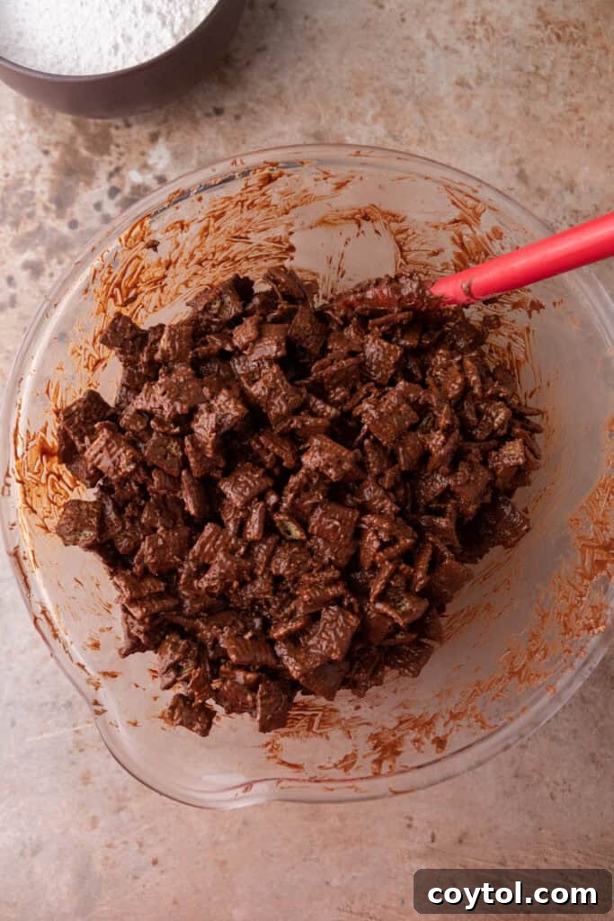 Chex cereal being gently folded to evenly coat with chocolate peanut butter mixture.