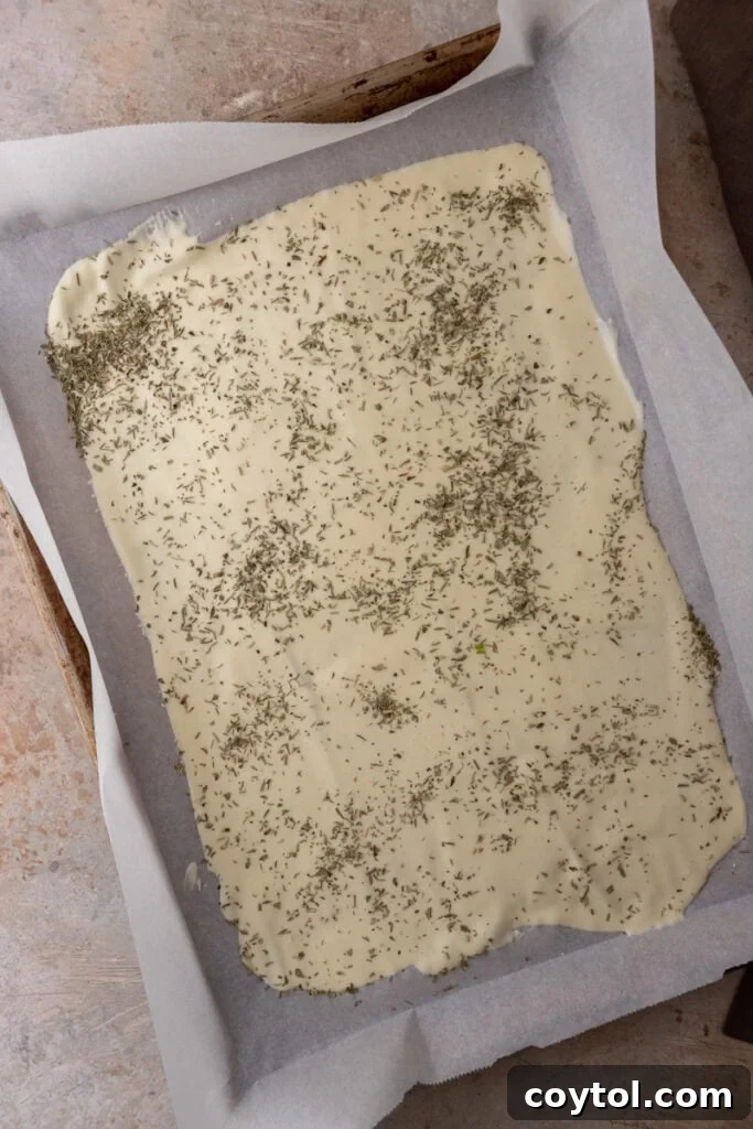 Seasoned sourdough discard dough spread thinly on a baking sheet