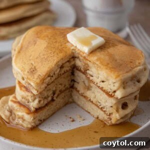 A stack of golden brown Sourdough discard Pancakes with syrup and berries.