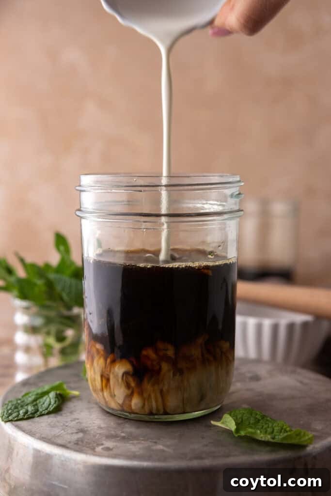 Hand pouring cream in a cup of coffee