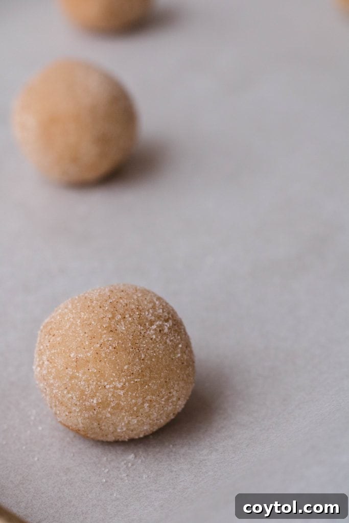 Hand rolling cookie dough balls in cinnamon sugar mixture for the best snickerdoodle cookies recipe