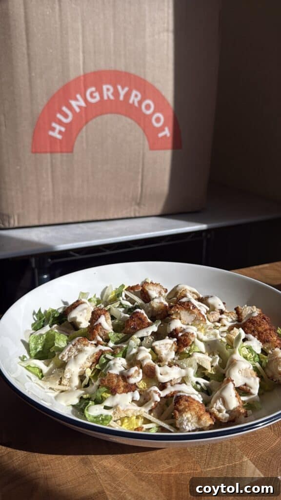 A fresh Caesar salad artfully arranged next to the neatly packed Hungryroot delivery box, showcasing the quality of ingredients.