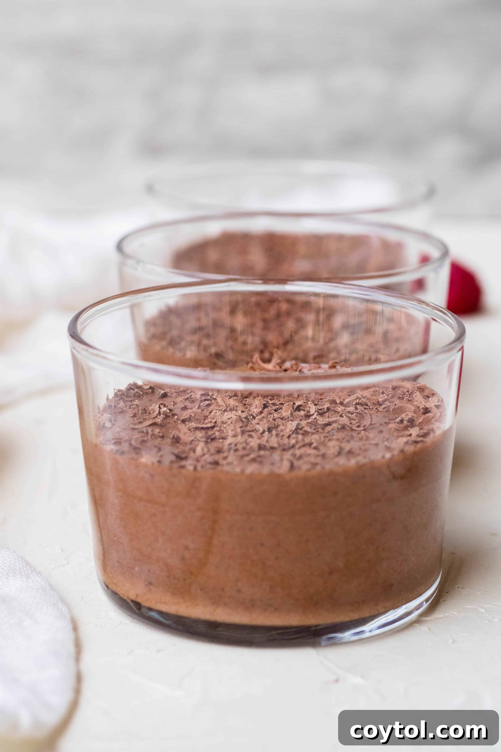 A close-up of light and fluffy vegan chocolate mousse with a glossy finish, served in a small glass cup, ready to be garnished and enjoyed.