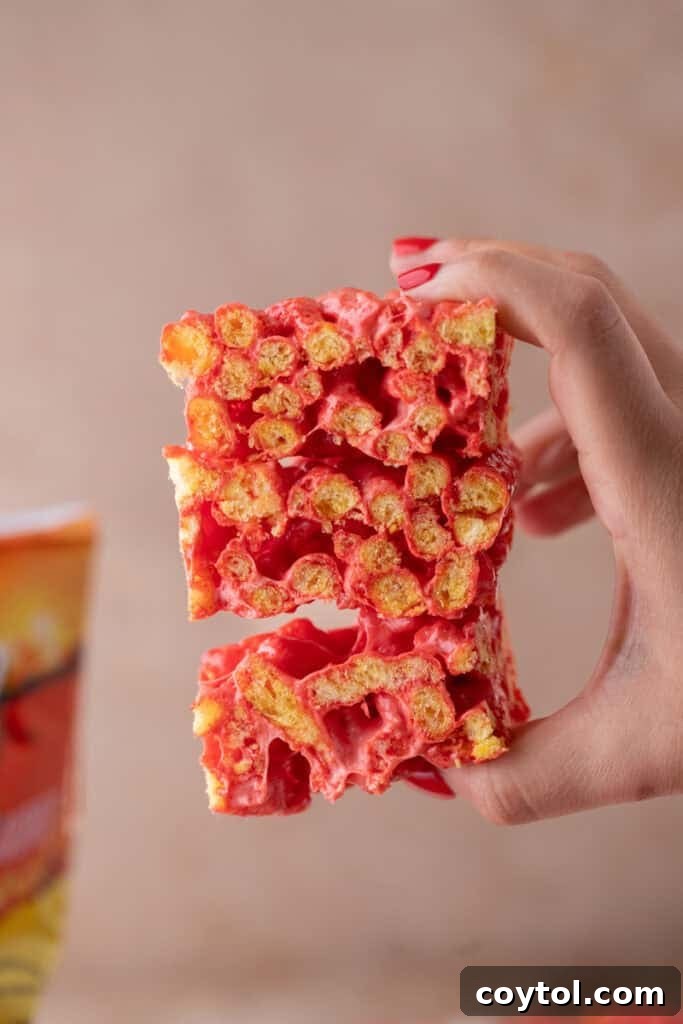 A hand holding a Hot Cheetos Marshmallow Crispy Treat, showcasing its unique appearance