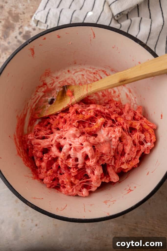 Hot Cheetos being mixed into melted marshmallows in a pot