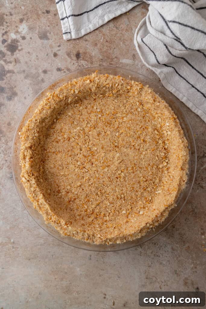 The Ultimate Salty Sweet Pretzel Pie Crust 11 Salty-sweet pretzel pie crust in a pie dish with a spoon, ready for a delicious filling.