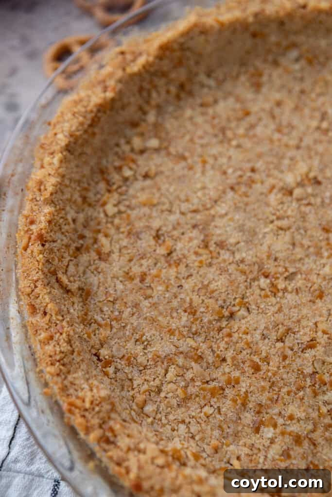 The Ultimate Salty Sweet Pretzel Pie Crust 12 Overhead view of a golden-brown baked pretzel pie crust in a pie dish, highlighting its texture.