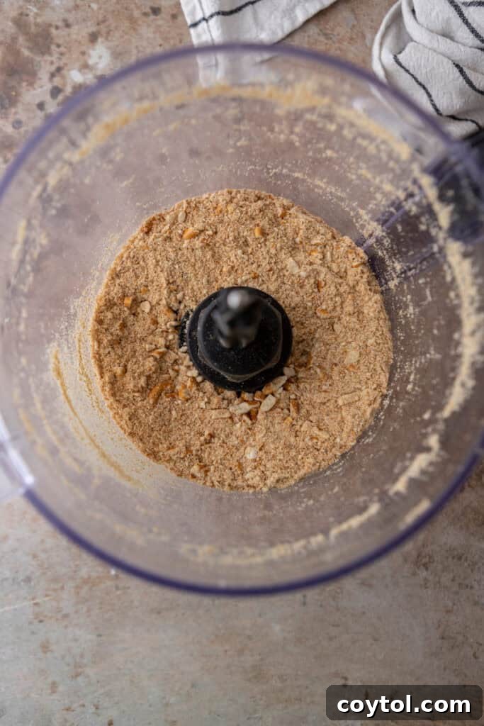 The Ultimate Salty Sweet Pretzel Pie Crust 5 Pretzel crumbs and sugar being added to a food processor for a pie crust mixture.
