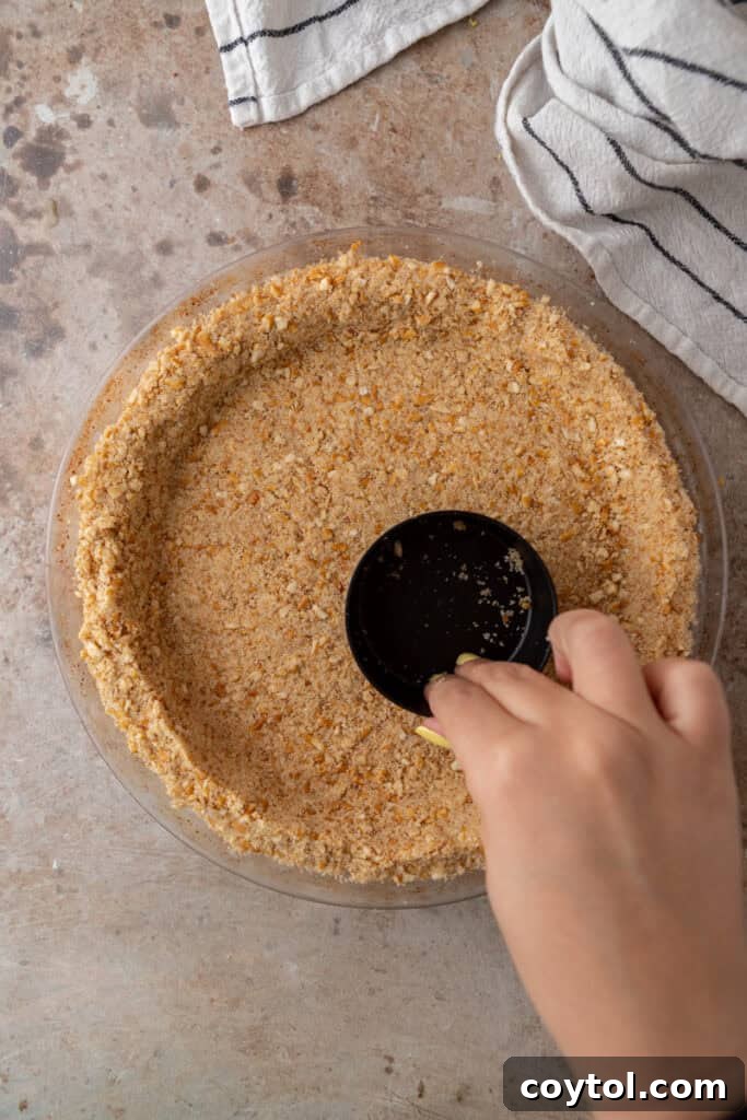 The Ultimate Salty Sweet Pretzel Pie Crust 8 Pretzel crumb mixture being pressed firmly into a pie pan to form the crust.