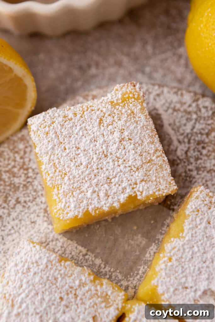 A very close-up shot of a small batch lemon bar, highlighting the fine dusting of powdered sugar.