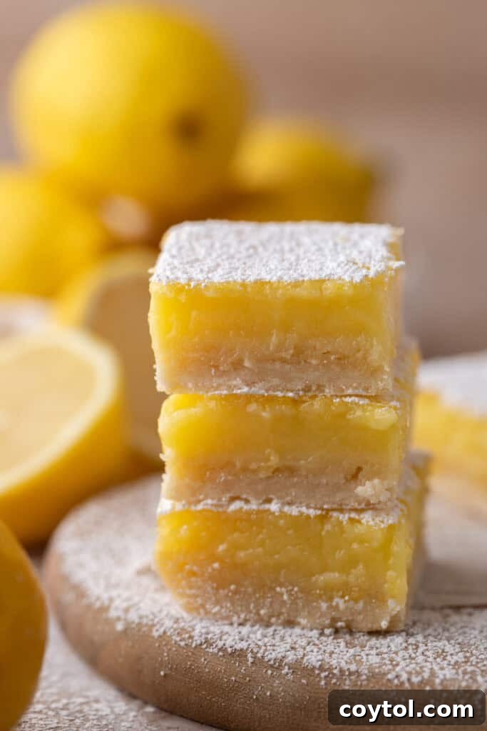 Three small batch lemon bars stacked neatly, showing off their golden crust and vibrant yellow filling.