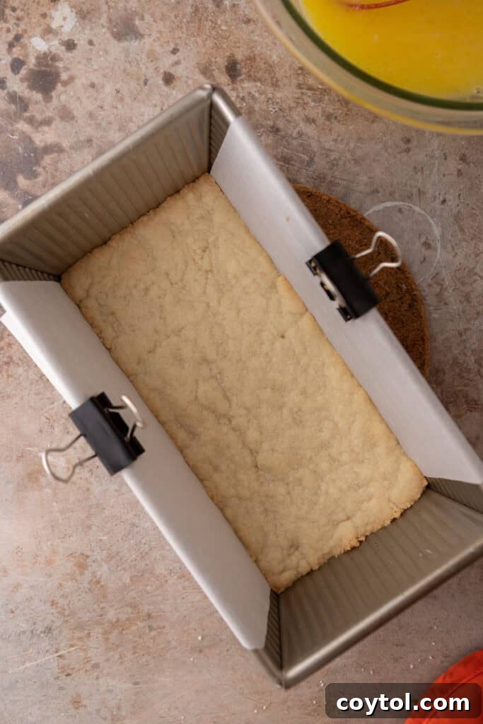 The pre-baked shortbread crust in a loaf pan, ready for the lemon filling.